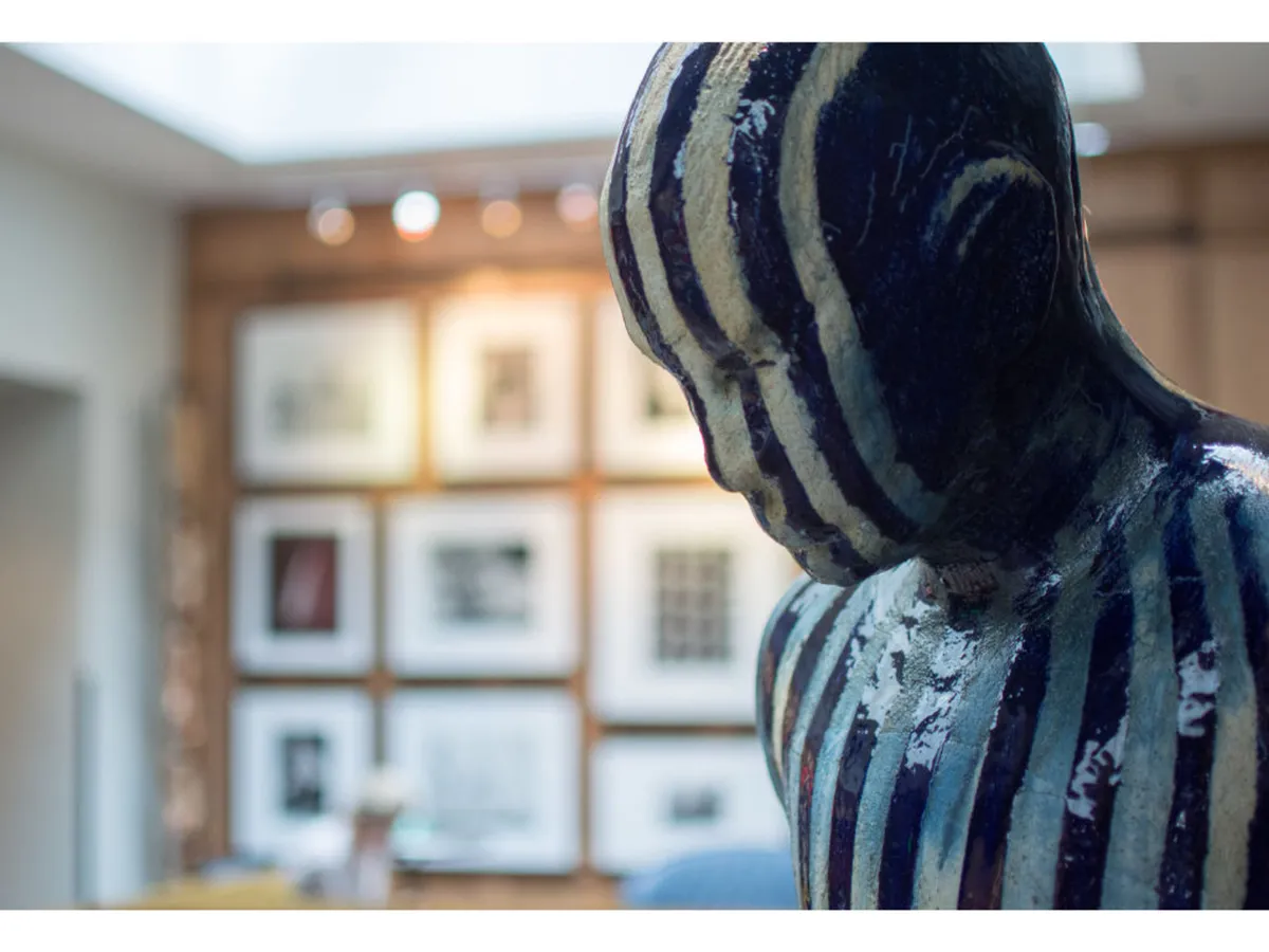 A thoughtfully arranged gallery wall with framed artworks and a striking striped sculpture in the foreground. The space feels creative and inviting, perfect for art critique, intimate conversations, or enjoying a curated gallery show.