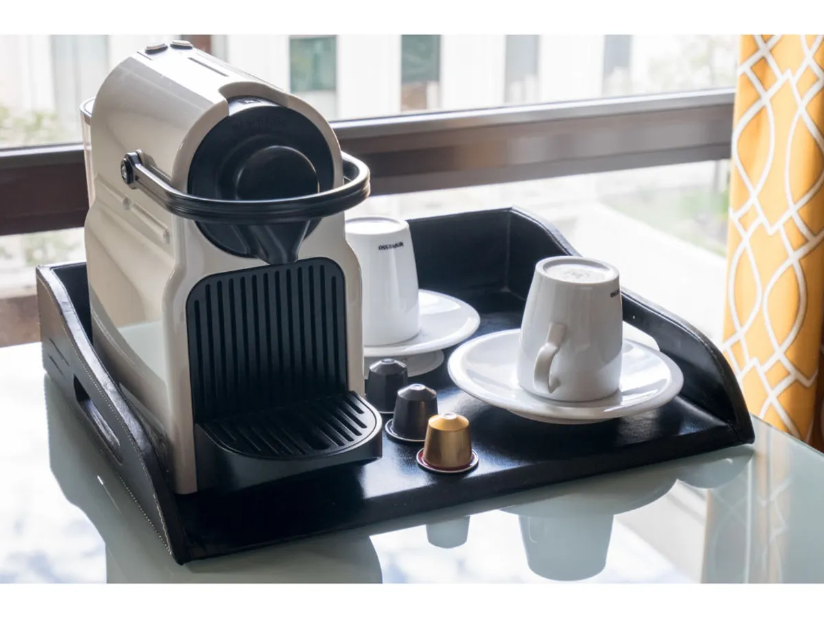 A close-up of a Nespresso coffee machine and cups arranged on a tray, inviting guests to enjoy a fresh coffee moment in the comfort of their room. The setup is cozy and welcoming, positioned to encourage relaxation or a leisurely start to the day.