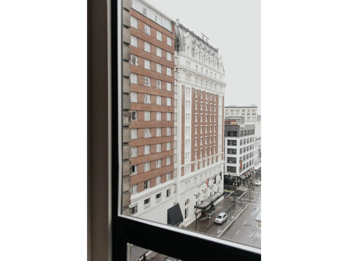 A nostalgic city view featuring historic buildings, a rain-soaked street, pedestrians, and the warm glow of nearby cafes and restaurants. The ambiance is quintessentially Portland, evoking the experience of exploring the city’s streets and architectural charm.